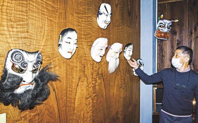 寺井重彦さんの木彫り神楽面を紹介する長男の親さん＝益田市あけぼの東町、ちいさなぎゃらりー・うつわ
