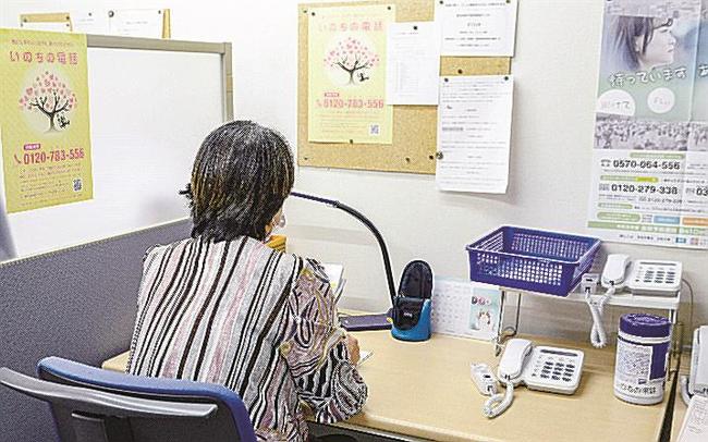 「いのちの電話」の電話相談を受けるデスクに座るスタッフの女性
