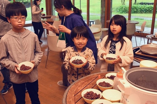 赤米と黒米の入ったご飯を手にする参加者=出雲市斐川町神庭、荒神谷博物館