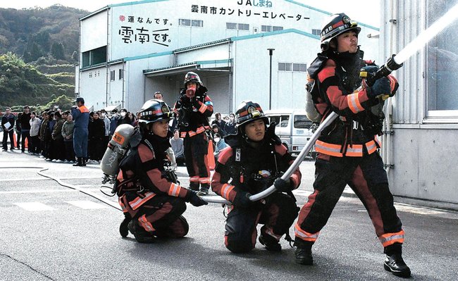 雲南消防署員による消火訓練の様子を見学する職員たち＝雲南市木次町山方、デルタ・シー・アンド・エス雲南工場