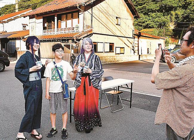 伝建地区の街並みを背景に子どもとの記念写真に応じるコスプレ参加者たち＝大田市温泉津町温泉津