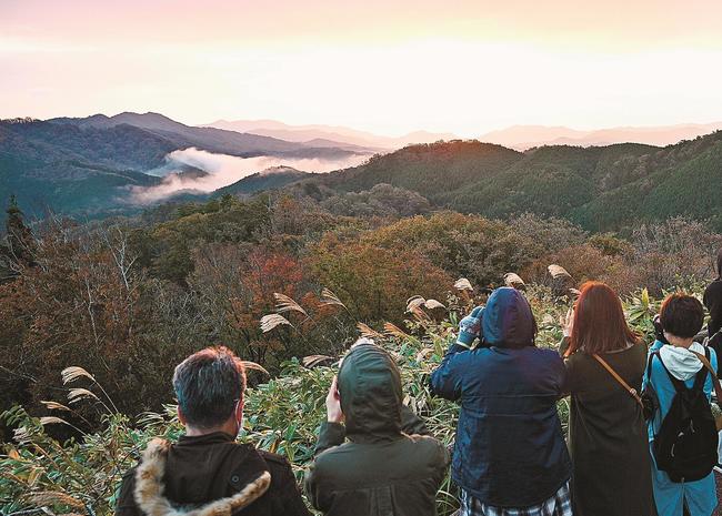 カメラやスマートフォンを構えて雲を待つ参加者ら＝島根県美郷町上野、田之原展望台