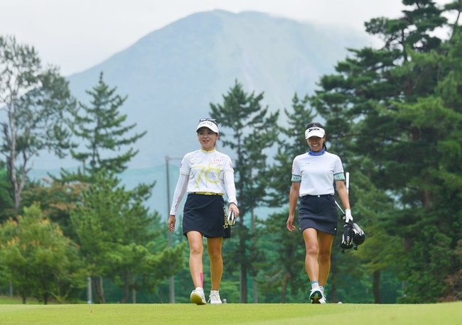 大山をバックに徒歩移動する選手たち＝2日、大山平原ゴルフクラブ