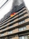 炎を上げるマンションの一室＝１８日午前７時４８分、松江市学園２丁目