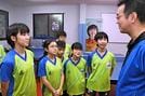 岡本慎司代表（右端）の話を聞く天津佳乃さん（右から２人目）と里穂さん（同３人目）＝浜田市竹迫町、ＯＴＳジュニア卓球練習場
