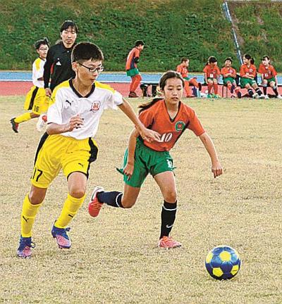 ピッチ上で競り合う選手＝雲南市大東町養賀、大東ふれあい運動場陸上競技場