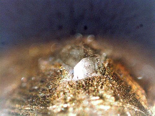 ダイヤモンドペンの先に埋め込まれたダイヤモンド（横幅約１ミリ）の拡大写真。土台は金属