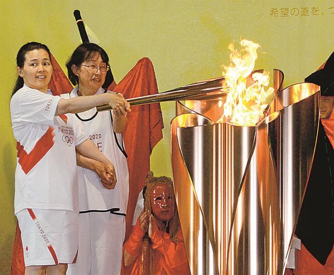 聖火皿に点火する最終走者の今本由紀さん（左）＝鳥取市布勢、布勢総合運動公園球技場