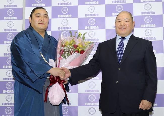 引退会見で、師匠の八角親方（右）と握手する元関脇の隠岐の海＝１４日、両国国技館
