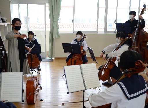 弓を持つ手の傾け方を指導する遠藤和子さん（左）＝安来市飯島町、安来第一中学校