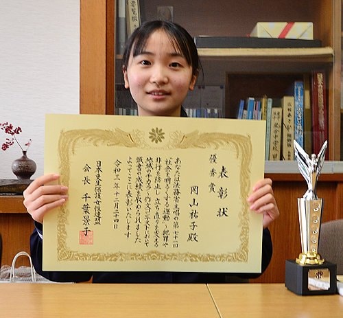 伝達式で受け取った表彰状を手にする岡山祐子さん＝浜田市旭町今市、旭中学校