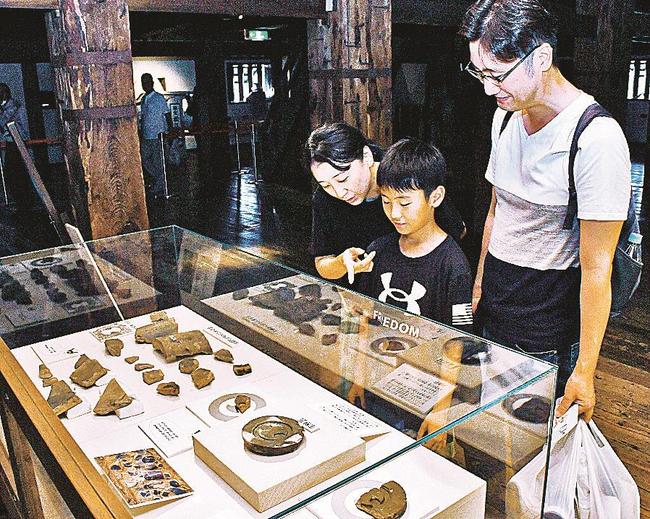 説明を読みながら、家紋瓦をじっくり見る親子＝松江市殿町、松江城天守
