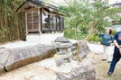 中村家の敷地内にある大きな腰掛け岩(左)とほこら。ほこらの中にさらに三つのほこらがあり、うち一つが和泉式部を祭っている=浜田市下府町