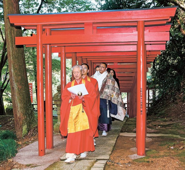 新しい鳥居の完成を祝い、渡り初めをする僧侶や奉納者ら＝安来市清水町、清水稲荷社