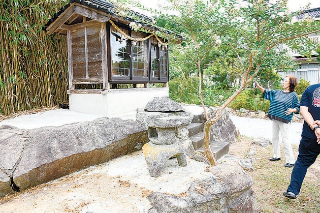 中村家の敷地内にある大きな腰掛け岩(左)とほこら。ほこらの中にさらに三つのほこらがあり、うち一つが和泉式部を祭っている=浜田市下府町
