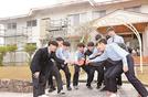 修繕工事が進む寮の前で円陣を組み、支援への恩返しを誓う松徳学院高校卓球部員＝松江市上乃木１丁目