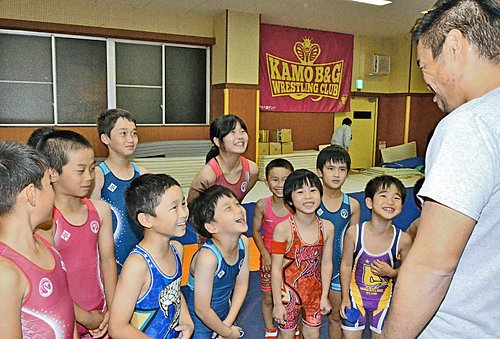 原恵介監督（右）の変顔に笑うクラブのメンバーと吾郷綺咲さん（中央奥）＝雲南市加茂町宇治、加茂Ｂ＆Ｇレスリングクラブ