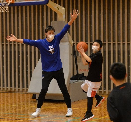 小学生と一緒にプレーしながら指導する小阪彰久選手（左）＝松江市鹿島町佐陀本郷、鹿島総合体育館