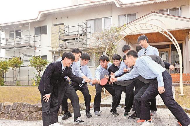修繕工事が進む寮の前で円陣を組み、支援への恩返しを誓う松徳学院高校卓球部員＝松江市上乃木１丁目