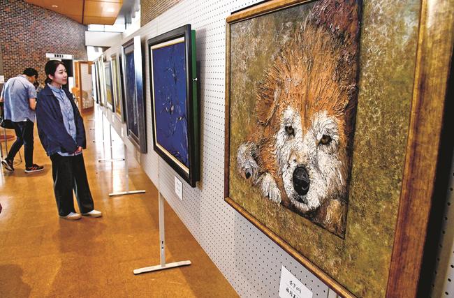 身近な題材を描いた斐川日本画協会の作品展を見る来館者＝出雲市斐川町直江、ひかわ図書館