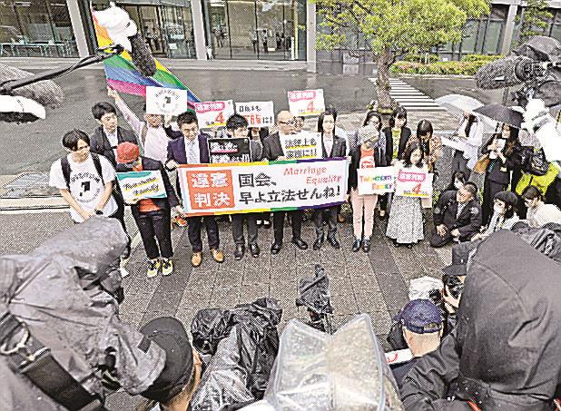 同性婚を巡る福岡地裁判決を受け、横断幕を掲げてアピールする原告ら＝８日午前、福岡市
