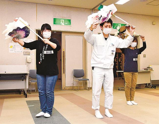 浜田石見神楽社中連絡協議会の会員（中央）から塩祓の動きを教わるメンバー＝浜田市黒川町、石央文化ホール