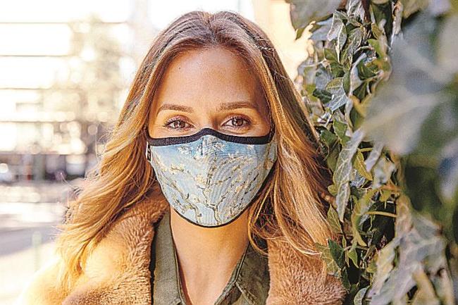 ゴッホの「花咲くアーモンドの木の枝」をあしらった「コウィコウィ」のマスクをした女性