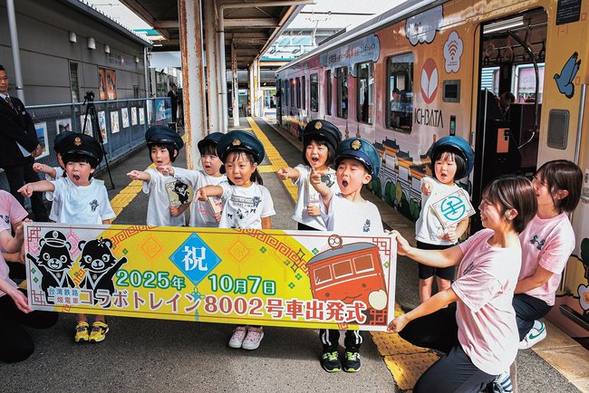 ラッピング車両の前で「出発進行」のポーズを取る子どもたち=松江市中原町、松江しんじ湖温泉駅