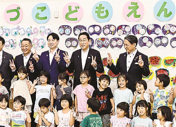 鳥取県日吉津村の子育て施設を訪問し、子どもたちと記念写真に納まる岸田文雄首相（後列右から２人目）＝２０２３年７月３１日（代表撮影）