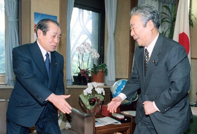 １９９９年１０月、事務引き継ぎを終え、野中広務前官房長官（左）と握手する青木幹雄新官房長官＝首相官邸