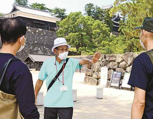 松江城で観光客を案内する松江市ボランティアガイドの会メンバー＝松江市殿町