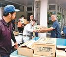 船で輸送された食糧を協力して運び入れる住民＝出雲市大社町宇龍、日御碕コミュニティーセンター