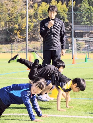 朝原宣治さんの指導で腕の力を鍛えるトレーニングに取り組む参加者=島根県吉賀町真田、真田グラウンド