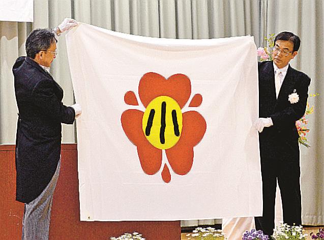 （９）新しい統合小学校の校旗を披露する山名毅校長（左）と倉吉市教育委員会の小椋博幸教育長＝４月１２日、同市仲ノ町、同校