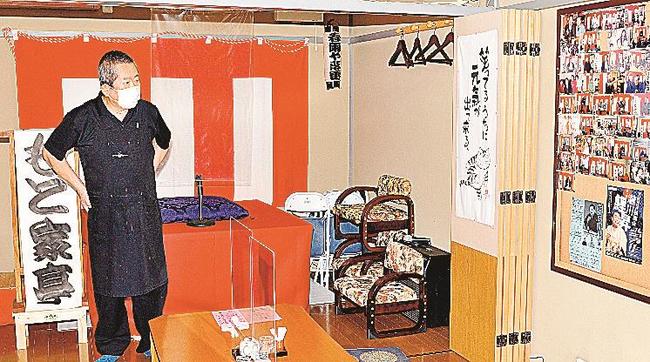 コロナ禍前に落語の寄席でにぎわった写真を見ながら、客足の回復を願う本山誠さん＝松江市末次本町、味処もと家