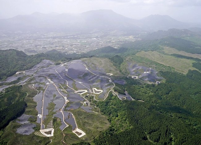 「阿蘇くじゅう国立公園」の周辺に建設された大規模太陽光発電所。奥は阿蘇山＝２０２３年５月、熊本県山都町（共同通信社ヘリから）