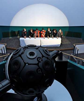 最新鋭のプラネタリウム装置の起動スイッチを押す関係者＝大田市三瓶町、サヒメル