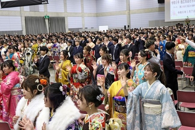 会場の記念撮影でカメラに向かい手を振る出席者