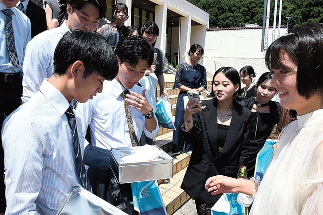 タイムカプセルを開けて当時を懐かしむ参加者＝島根県隠岐の島町西町、隠岐島文化会館