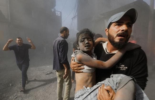 イスラエル軍の空爆で負傷した子どもを運ぶパレスチナ人男性＝１０月２６日、ガザ地区南部ハンユニス（ロイター）