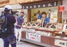 川崎大師の参道沿いで、あめ専門店を紹介する磯谷祥太さん（左から２人目）