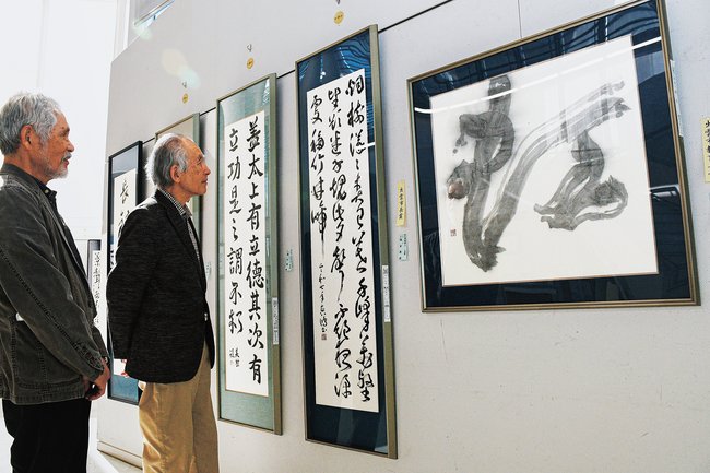 作品に見入る杉原恒心会長(右)=出雲市駅南町1丁目、ビッグハート出雲