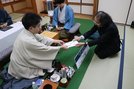 1日目の対局を終え、封じ手を立会の福崎文吾九段（右）に手渡す菅井竜也八段（左）。奥は藤井聡太王将＝大田市、国民宿舎さんべ荘（提供：日本将棋連盟）