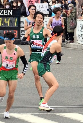 昨年の全国都道府県対抗男子駅伝の３区で１０人抜きを果たし、次の走者にたすきを渡す鳥取・岡本直己選手（中央）＝２０２３年１月２２日、広島県廿日市市