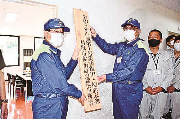 現地事務所の看板をかける平井伸治知事（左）と奥本倫久所長＝鳥取市佐治町加瀬木、鳥取市佐治町コミュニティセンター内