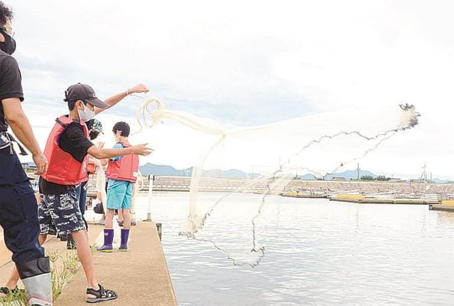 投網に挑戦する小学生ら＝出雲市平田町、平田宍道湖漁港