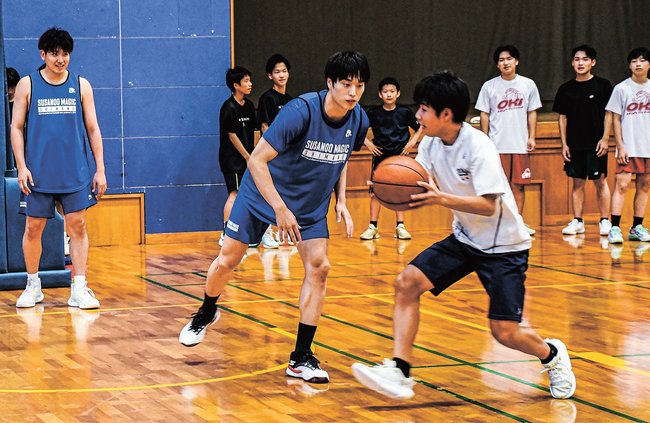 中学生にディフェンスの手本を見せる飯尾文哉選手（左）と岡田侑大選手（中央）＝島根県隠岐の島町栄町、町総合体育館