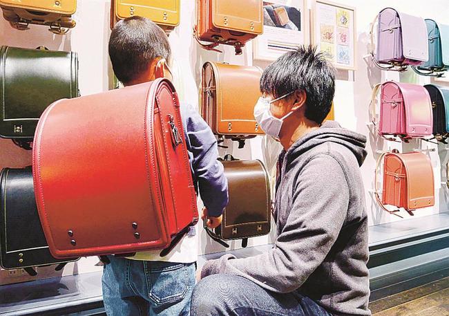 機能的なデザインのランドセルが並ぶ土屋鞄製造所の「童具店・横浜」で商品を選ぶ親子＝４月、横浜市