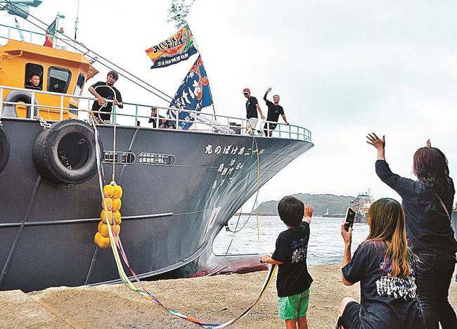 家族らの見送りに応えながら出漁する沖合底引き網漁船の船員＝浜田市原井町、浜田漁港
