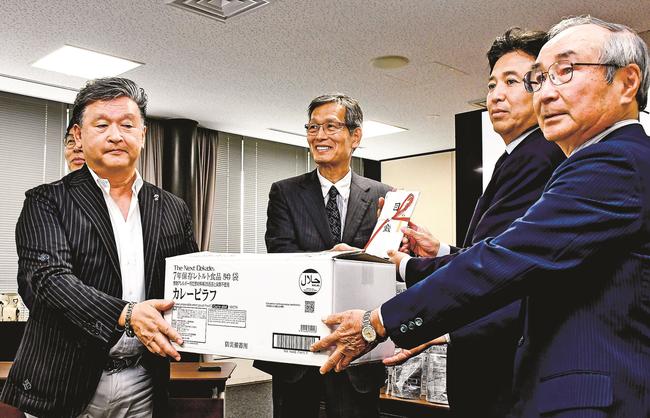 長期保存レトルト食品を寄贈する笠浩一郎代表（左）＝出雲市今市町、市役所